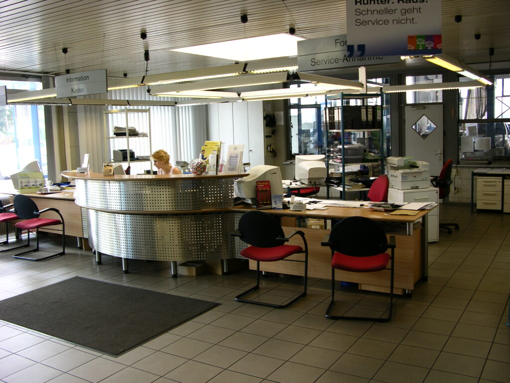 Empfangs- und Service-Annahme des Autozentrum Epple in Rutesheim mit Rundtheke, Mitarbeiterin und Beschilderung ‚Information / Kasse‘